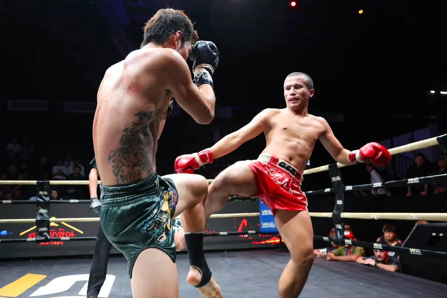 Two Muay Thai fighters exchange a low kick in the SRC ring
