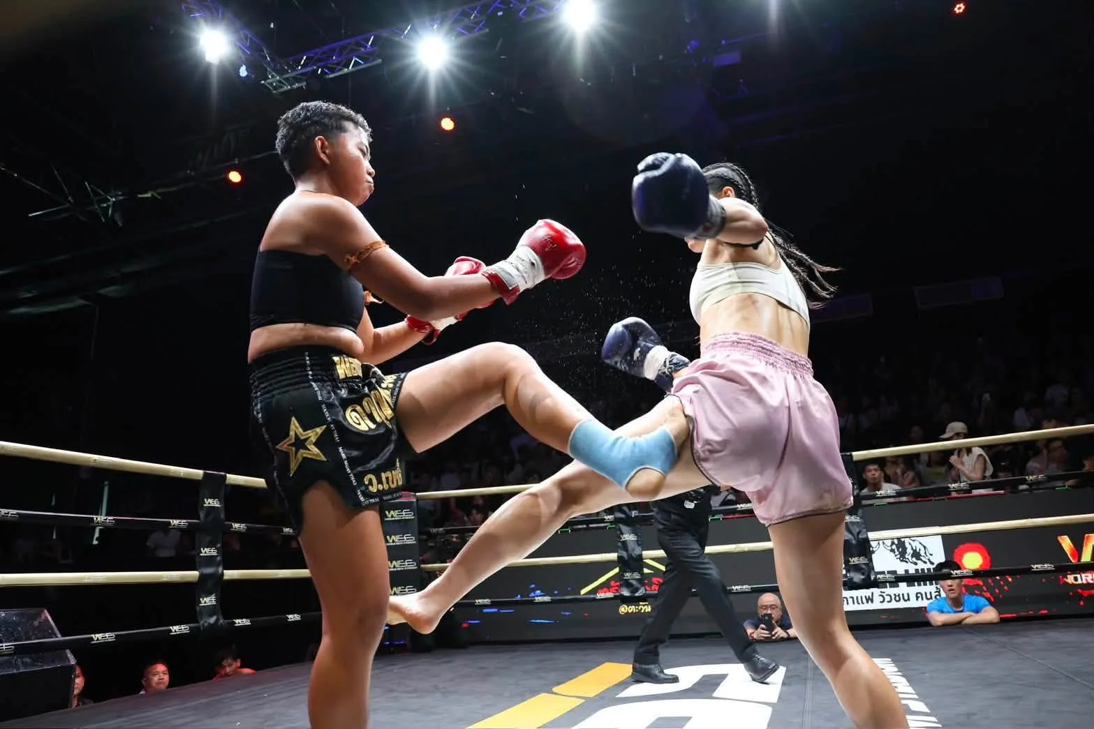 Two women exchange kicks during an SRC Muay Thai bout