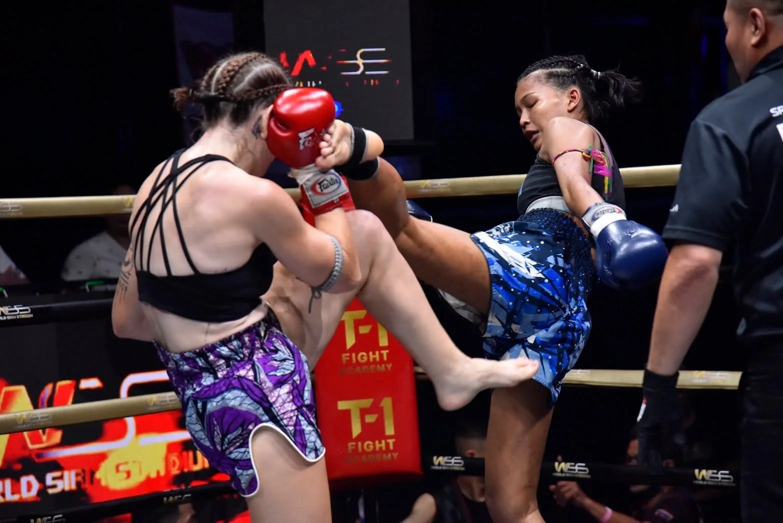 Two women exchange knees in a clinch during an SRC bout