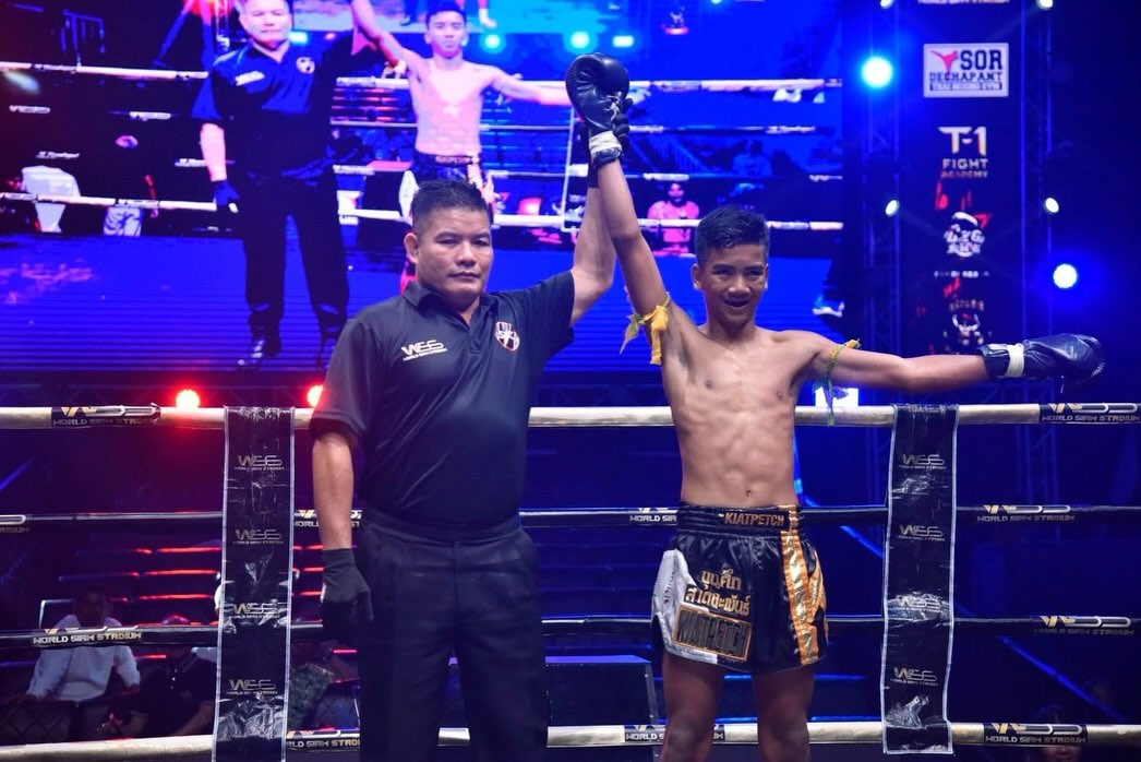 A fighter celebrates as the referee raises his glove
