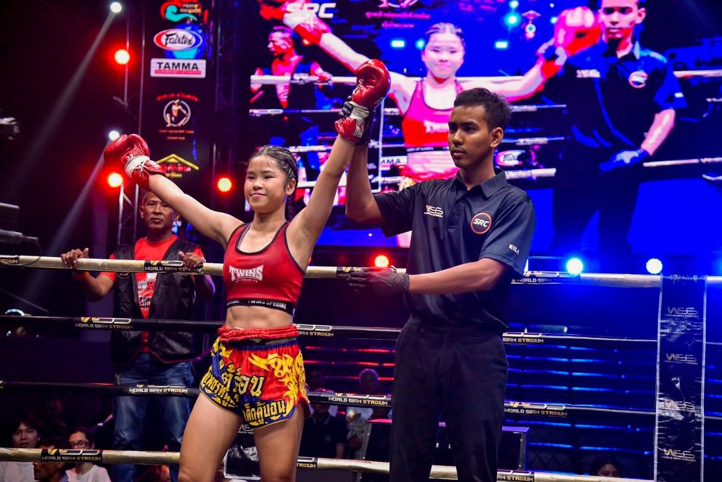 A female fighter celebrates her win with her glove raised