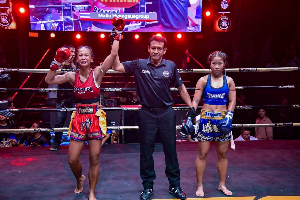 A fighter celebrates his victory beneath the ring lights